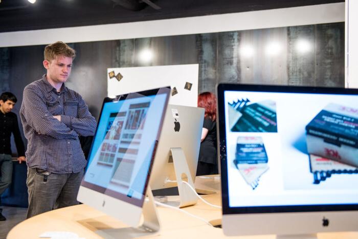 Mac computers showcasing digital media in a gallery.
