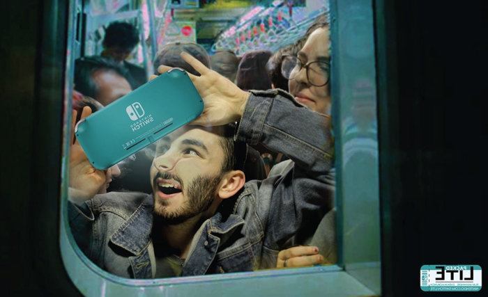 Young adult squished into a subway train, but still enjoying their handheld video game system.
