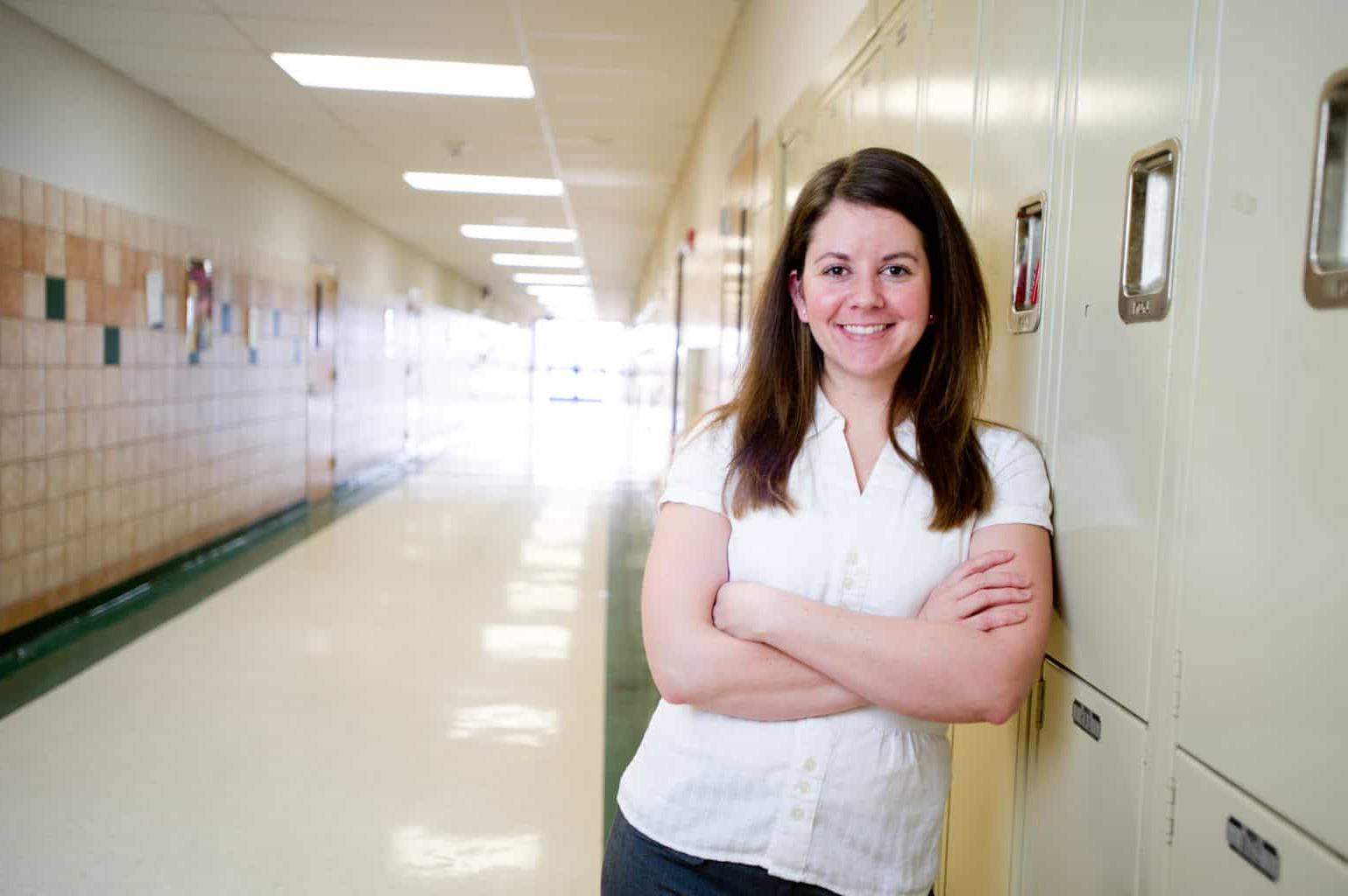 Woman school counselor standing in front of lockers.