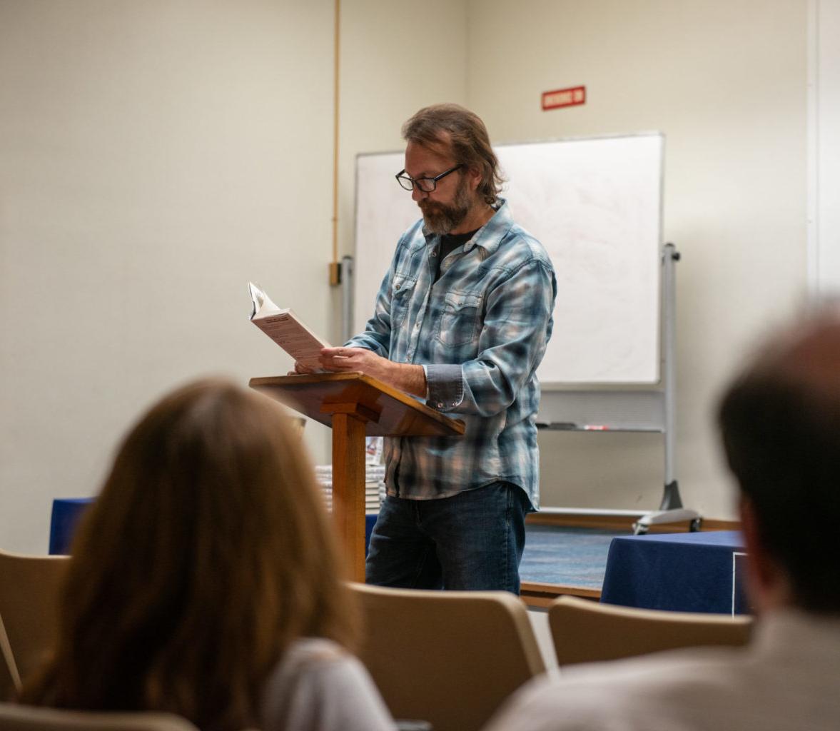 Man reading book to a classroom.