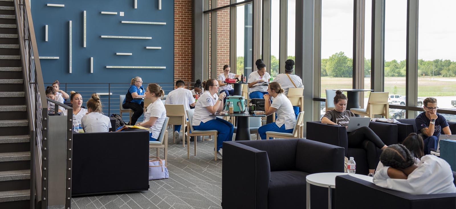 different groups of students eating, reading and talking in a student lounge at the Rellis location.