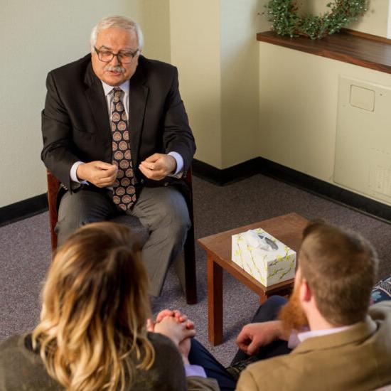 A heterosexual couple speaking with a male therapist.