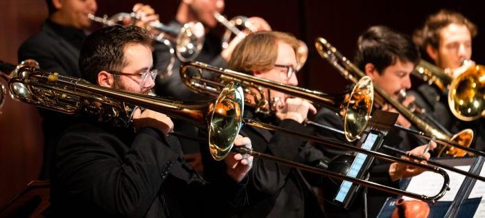 A group of individuals playing the trombone.