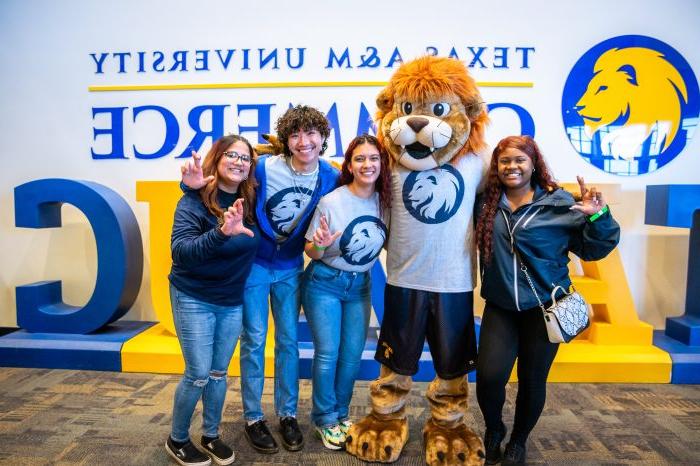 Four students pose with Lucky the Lion mascot.