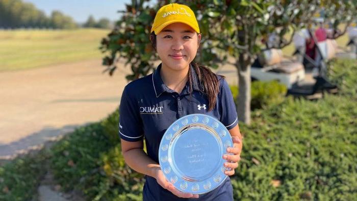 Golfer smiles at camera while holding a silver commemorative plate